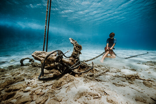 child trying to pull old anchor and chain underwater