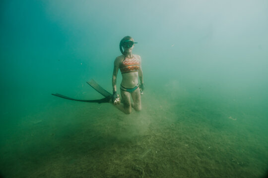 freediver hovering above polluted seabed during cleanup