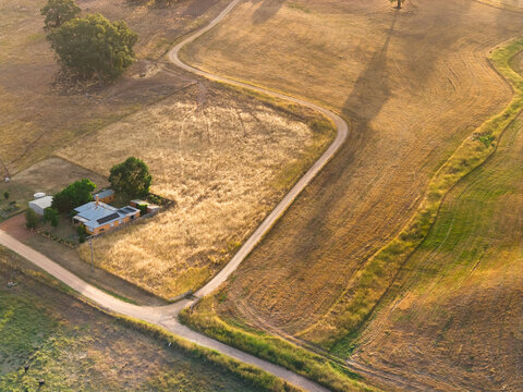 Country road zig zagging up a hillside past a rural farmhouse