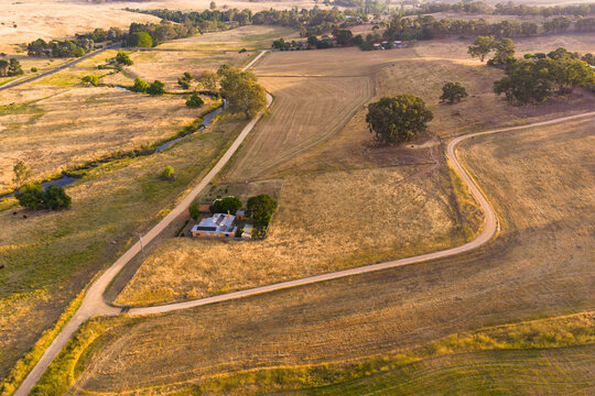 Country road zig zagging up a hillside past a rural farmhouse