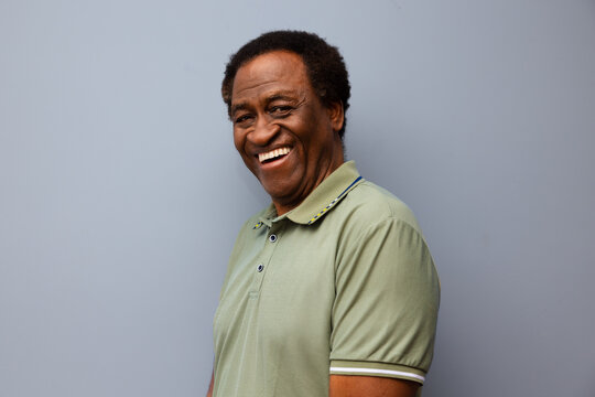 Smiling man in a green polo against gray background