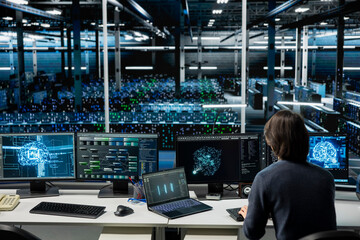 IT expert using PC in high tech server hub with gear supporting deep learning scientific...