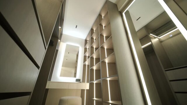 Modern minimalist walk-in wardrobe with wooden shelves and LED lighting.