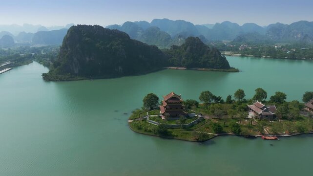Aerial view of Chua Vang Pagoda, a popular destination for tourists and pilgrims, located in Ninh Binh, Vietnam. Mountains in the background.