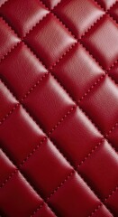 Fototapeta premium Deep red quilted material displays a luxurious diamond stitch pattern