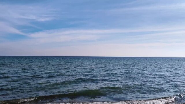 Serene Deep Blue Sea Ripples under a Soft Pastel Sky at Dusk. Calm Ocean Waves with Horizon Line and Light Cirrus Clouds. Minimalist Nature Background for Meditation and Travel Concepts.