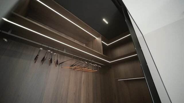 Modern minimalist walk-in wardrobe with wooden shelves and LED lighting.