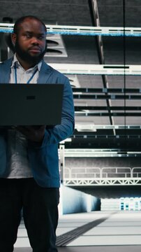 Vertical video Optimizing electronics, laptop and team of software developers in server farm. Brainstorming, notebook and teamworking colleagues in data center monitoring system performance