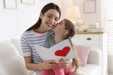 Happy Mother's Day. Little girl greeting her mom with holiday card on sofa indoors
