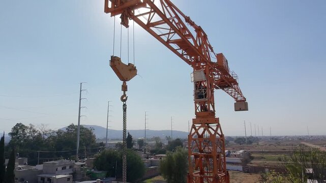 Desplazamiento lateral de drone revelando gr&uacute;a torre bajo cielo azul despejado
