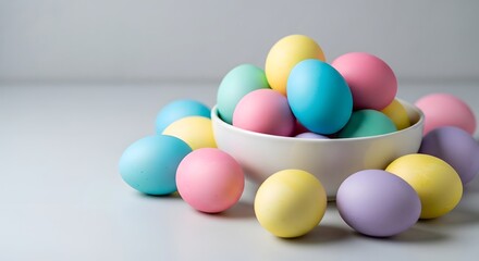 Pastel colored Easter eggs in a white bowl on a minimalist light gray background. Spring holiday still life concept with copy space.