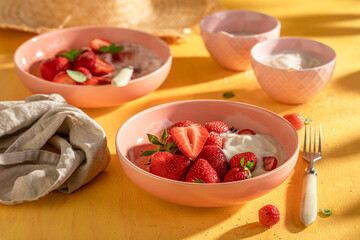 Homemade and delicious strawberries on yellow sunny table.