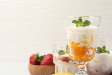 Fototapeta premium Tasty yogurt with mango and mint on white table, closeup. Space for text