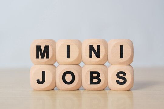 Wooden cubes forming text MINI JOBS on table with clean background. Concept of part time work, freelance opportunities, side income and flexible employment.