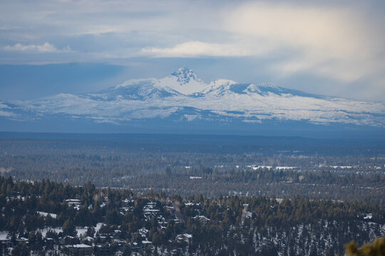 A mountain range is visible in the distance, with snow covering the peaks. The sky is cloudy, and the mountains are in the background