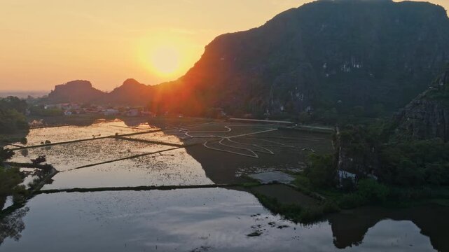 Scenic sunset view of limestone karsts reflecting in the water in Hang Mua, Ninh Binh, Vietnam. The landscape is a popular tourist destination.