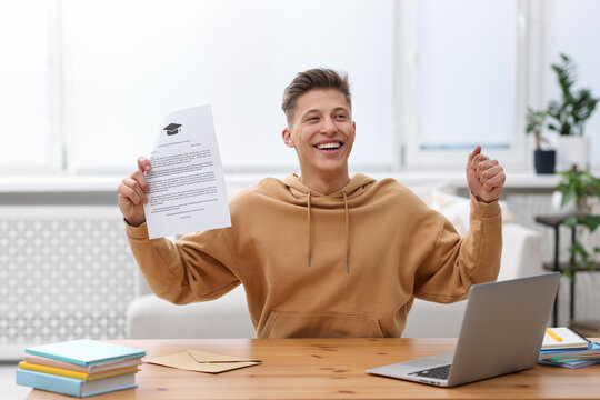 Happy man with acceptance letter from university at table indoors