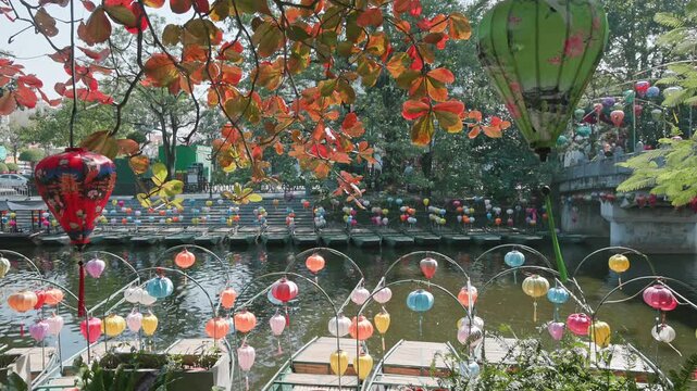 A row of boats decorated with colorful lanterns line the shore of Hoa Lu Old town, Ninh Binh, Vietnam. The boats are waiting for tourists to take them on a tour.