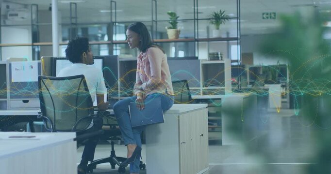 Woman lowering laptop leaning into coworker causing waveform overlay on monitor for business review