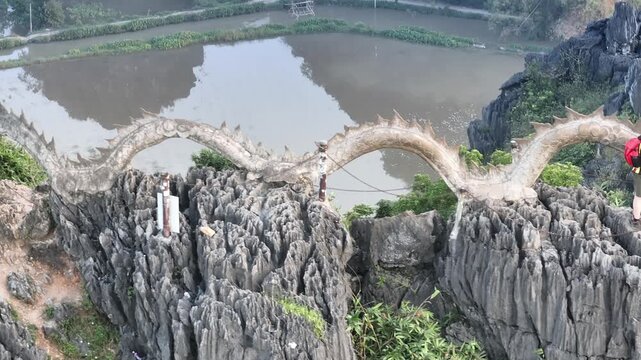 A dragon statue atop Mua Caves, offering panoramic views of Tam Coc's rice paddies and limestone karsts.