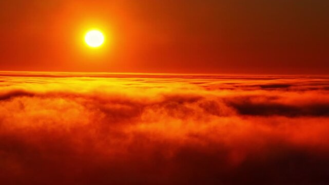 High altitude drone shot of a fiery orange and red sunset with the bright sun shining through fast-moving clouds