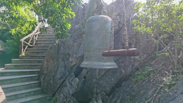 A large bronze bell hangs at a Pagoda, a popular tourist destination in Hoa Lu Old town, Ninh Binh, Vietnam. The bell is rung to call monks to prayer and for special occasions.