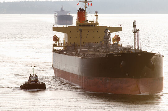 Canada, BC, Vancouver.  Freighter is escorted under the Second Narrows bridge in the Burrard Inlet by harbour tugs.