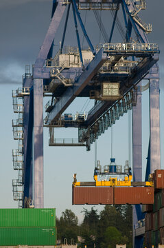 Canada, BC, Surrey.  Surrey Fraser Docks.  Crane loading containers onto freighter.