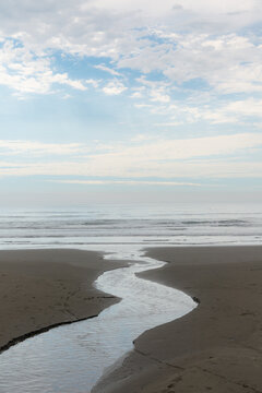 USA, WA, Queets.  The Olympic Peninsula.  A small, fresh water stream flowing across the beach to the  Pacific Ocean.