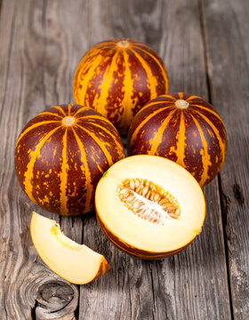 Tigger Melon Variety Showing Orange Stripes on Weathered Wood Surface
