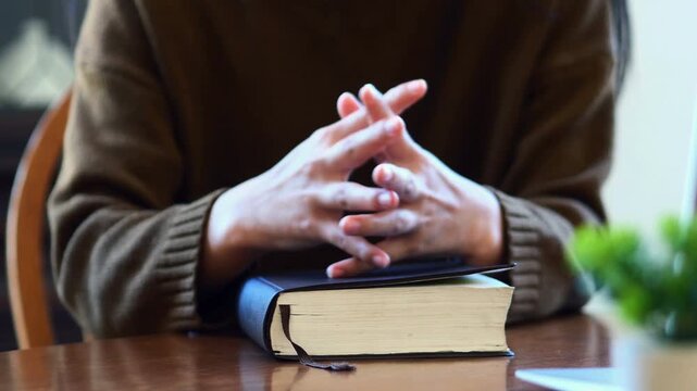 Christian Woman hands while reading the Bible outside. praying to God with hands held together	