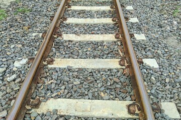 Naklejka premium ​Close-up of rusty steel rails on concrete sleepers and grey stone ballast.