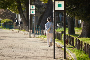 春の名城公園で犬を連れて散歩する若い女性の姿