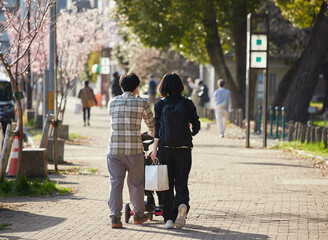 春の名城公園でベビーカーを持って散歩する若い夫婦の姿