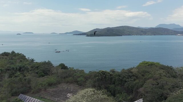 Calm Blue Water and Distant Islands Unfold Beyond the Forested Shoreline in Paraty, Brazil - Aerial Drone Shot