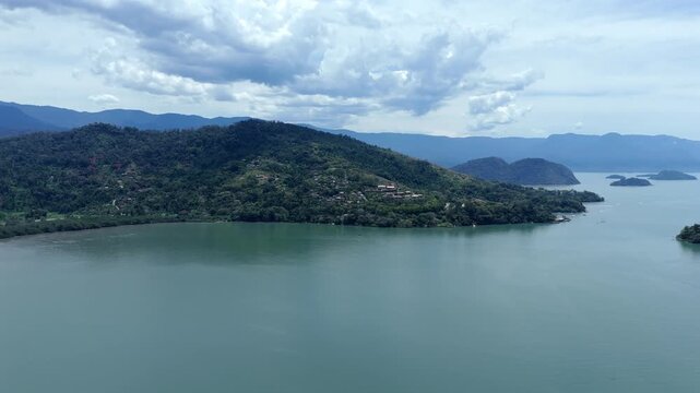 Paraty, Brazil - A Forested Island Rises From Calm Coastal Waters Beneath Drifting Clouds - Aerial Drone Shot