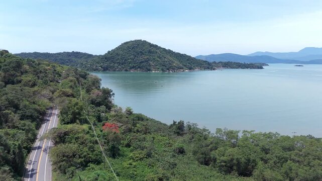 Coastal Road Winding Through Lush Green Mountains With A View Of Ilha Do Joao Araujo Near Paraty, Brazil. - aerial shot