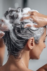 Naklejka premium Woman washing her hair with shampoo in the shower, enjoying a refreshing and cleansing experience