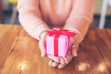 Close up woman hands wrap present gift in cozy living room. Woman wrapping christmas gift box under...
