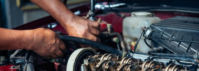 Obraz premium Banner Close up Mechanic man hands repairing car auto repair shop. Banner Man hands fixing machinery check vehicle mechanical motor service. Vehicle Car overhaul maintenance engineer with copy space