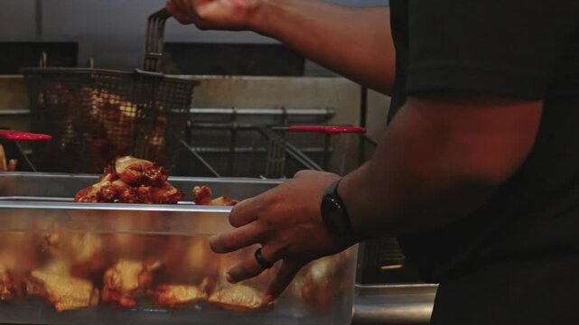4K close-up footage of fried chicken wings in bulk being dumped into a serving tray, capturing crispy texture, golden breading, and fresh hot food preparation.