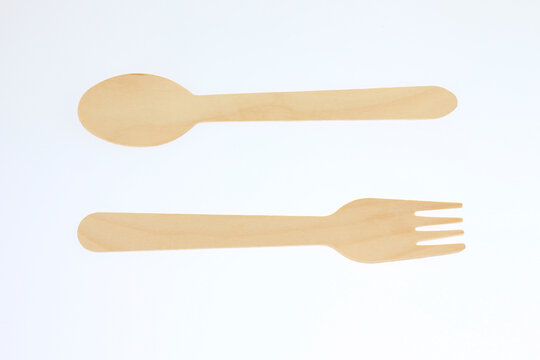 Simple wooden spoon and fork lie against a clean white background. They appear fresh, unbroken, and unused. Minimalist design emphasizes natural wood texture and smooth edges. good for home cooking