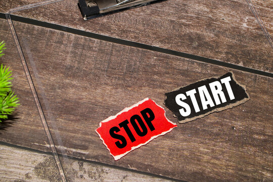 Stop and start words on torn paper over wooden background.Change management and habits concept.