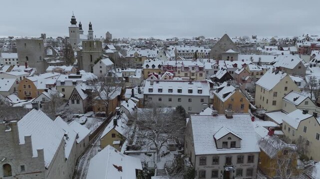 Winter Drone Flight Across Snow-covered Visby Old Town Ruins and Cathedral, Gotland Sweden