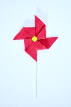 Handmade red wind whell paper isolated on vertical white background.