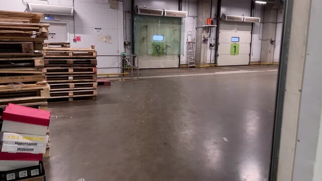Industrial warehouse loading dock area with numbered roll-up doors and stacked wooden pallets. Modern logistics center interior for efficient cargo receiving, shipping and supply chain.