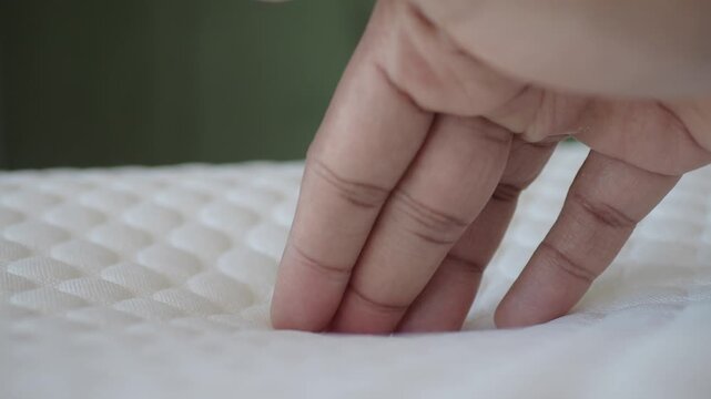 Hand pressing into soft white mattress showing comfort and support for sleeping