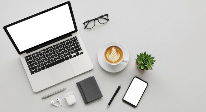 A modern workspace setup with a laptop, coffee cup, and office supplies on a white desk.