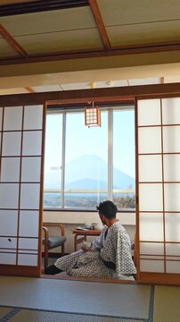 Traveler enjoying tea in a traditional ryokan with Mount Fuji view, Japan