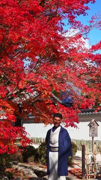 Young man in kimono walking through autumn scenery in Japan